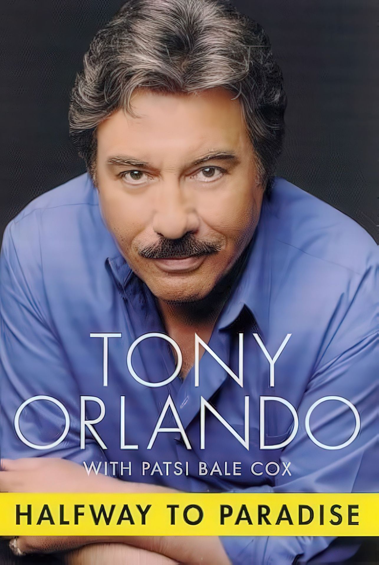 Portrait of Tony Orlando with a thoughtful expression, wearing a blue shirt, with the title 'Halfway to Paradise' displayed prominently below.