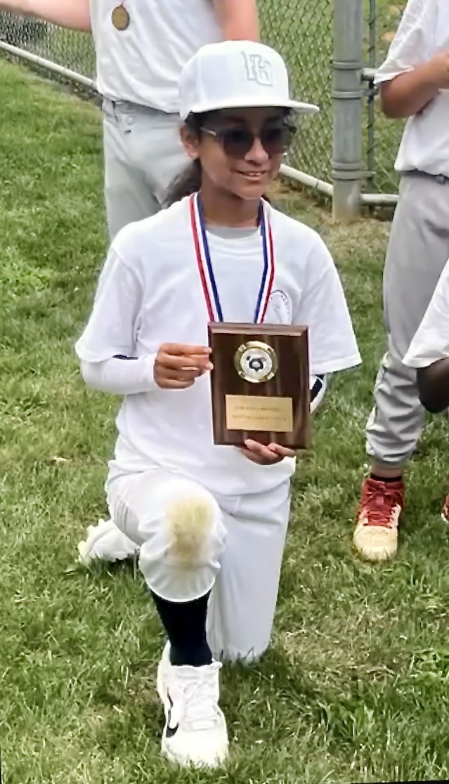 A young player kneeling with a Dom Scala Baseball award